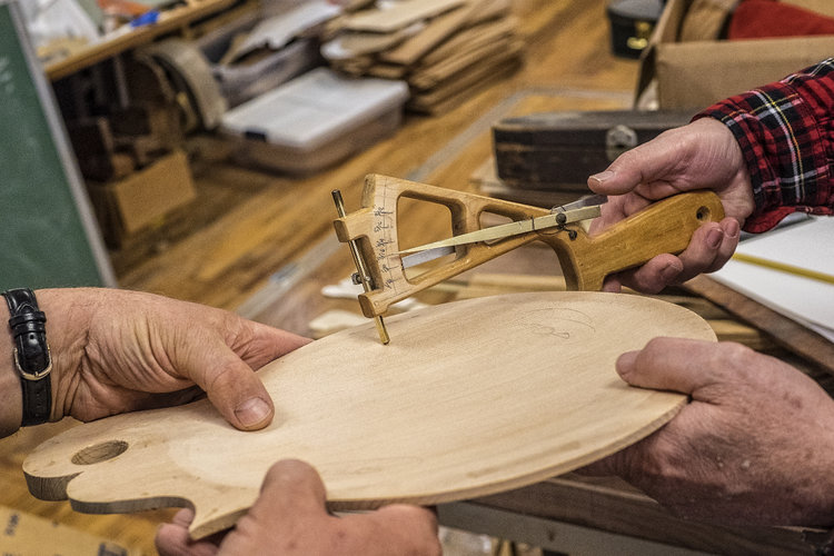 hands hold an instrument and tools at the troublesome creek stringed instrument company in knott county, kentucky. it is located in hindman