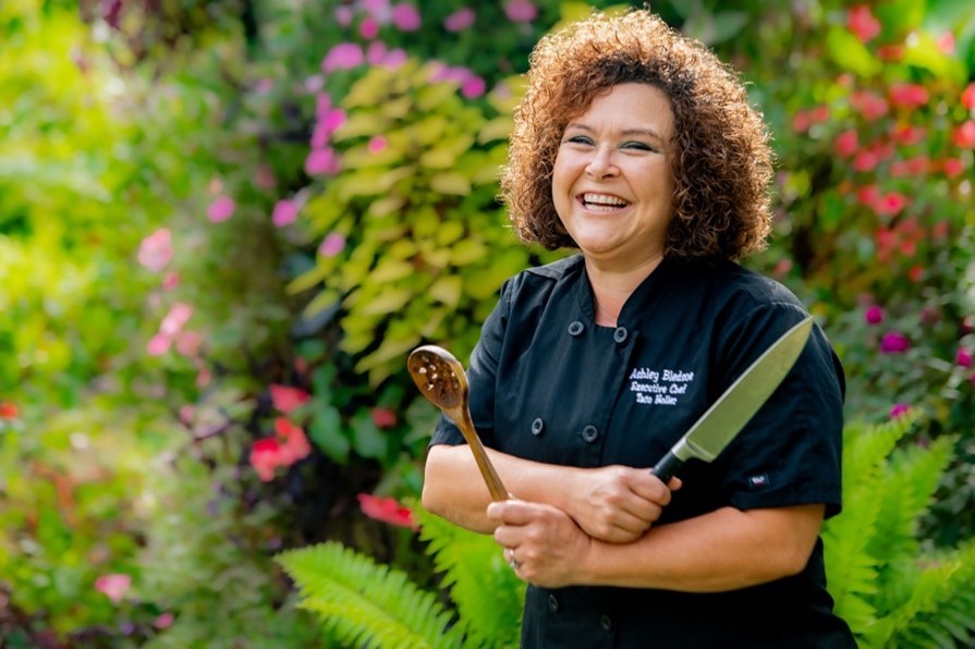 ashley bledsoe stands with her chef knife and spoon at oak hill gardens posing for her professional headshots