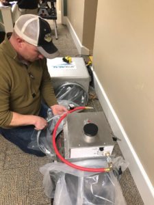 A man sets up energy efficiency equipment. The training is part of building an energy efficiency and solar workforce