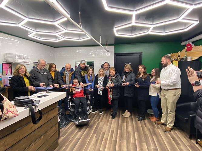 Ribbon cutting at the new shop in downtown Hazard picturing a bunch of people cutting a ribbon