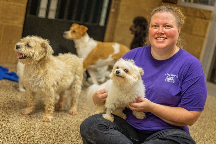 Ashley Renton smiles while holding a dog at her business For Paws Unleashed in Richmond, Kentucky. MACED supports them with a loan