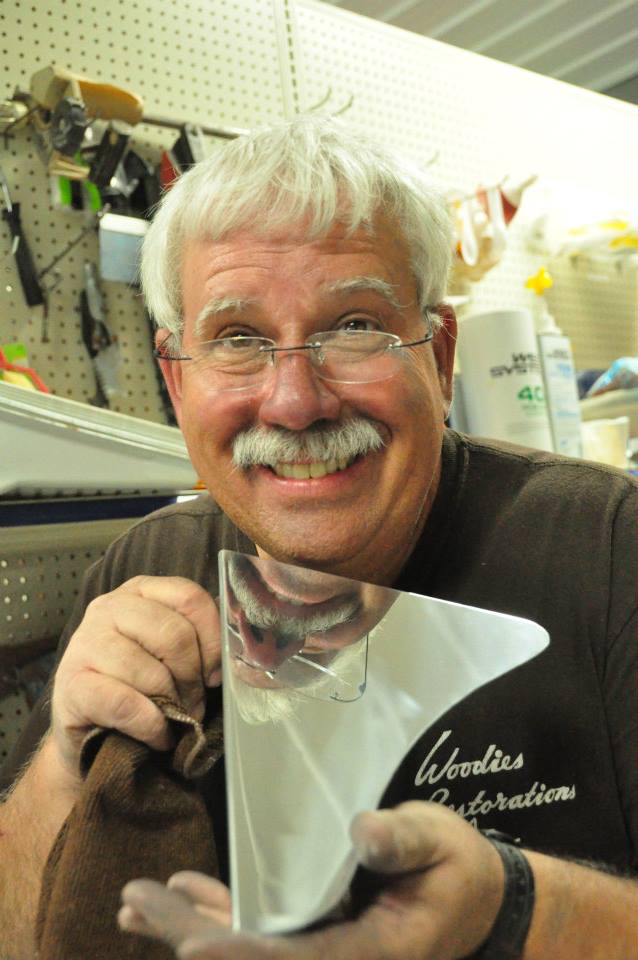 Paul Cundiff smiles while holding a boat piece during a repair