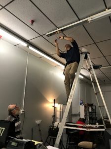 A man stands on a ladder while doing an energy efficiency audit in eastern kentucky, part of building clean energy