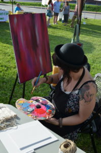 A woman sits at an easel in the grass in eastern kentucky.
